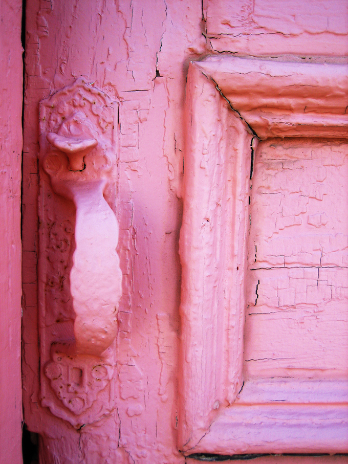 Close up of pink door with cracking paint