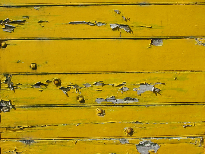 Yellow paint peeling from wooden wall