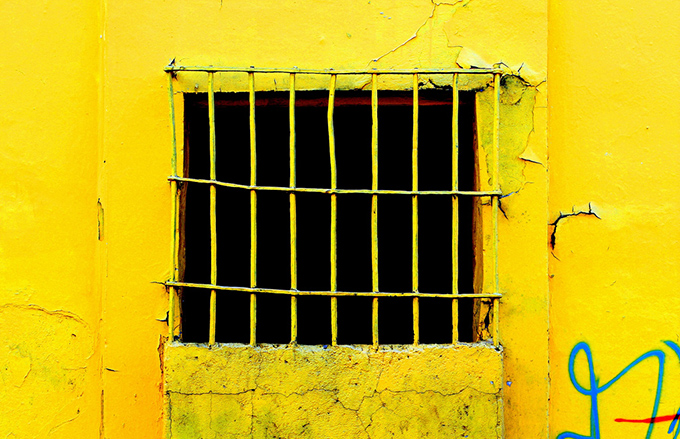 Aged yellow wall and window with a grill