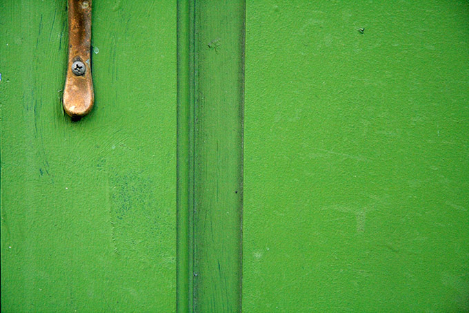 Close up of green wood door an rusting handle