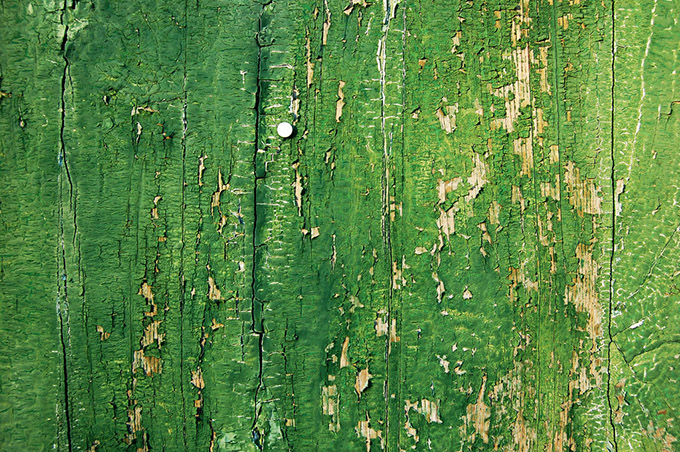 Green wooden fence with flaking paint