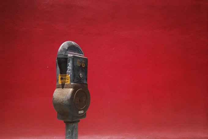 Old parking meter infront of a red wall