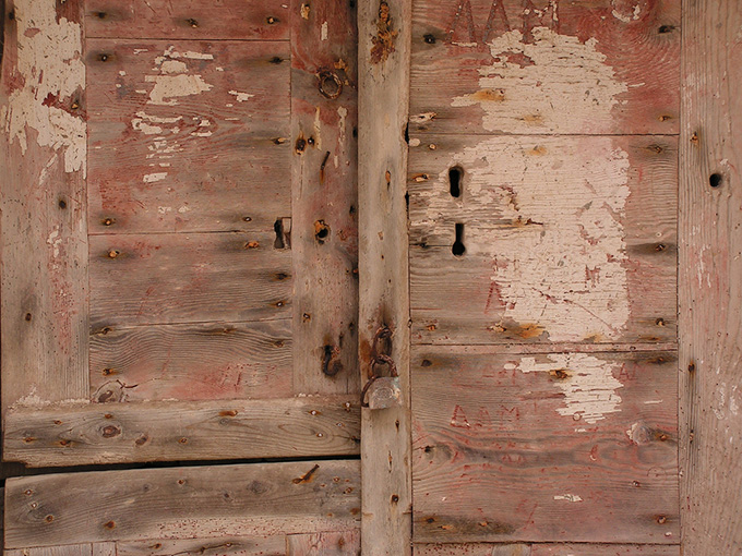 Old aged door with rusted lock and many keyholes