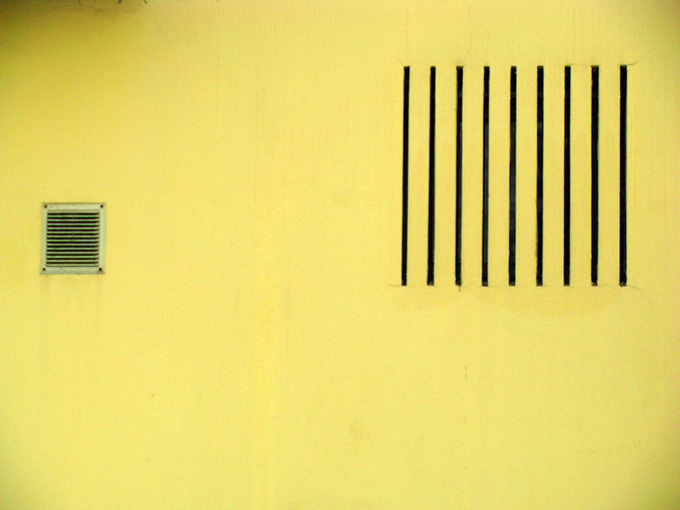 A yellow wall with air vents