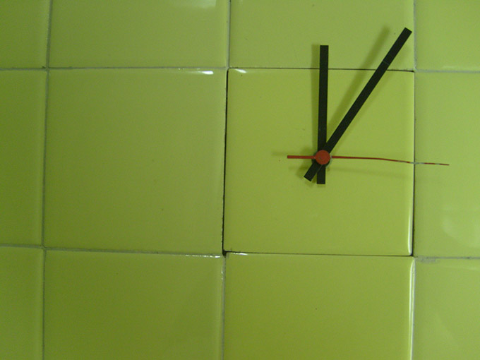 Clock hands on a green tiled wall