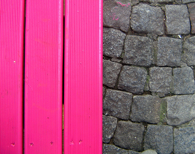 Pink wood fence against a grey brick wall